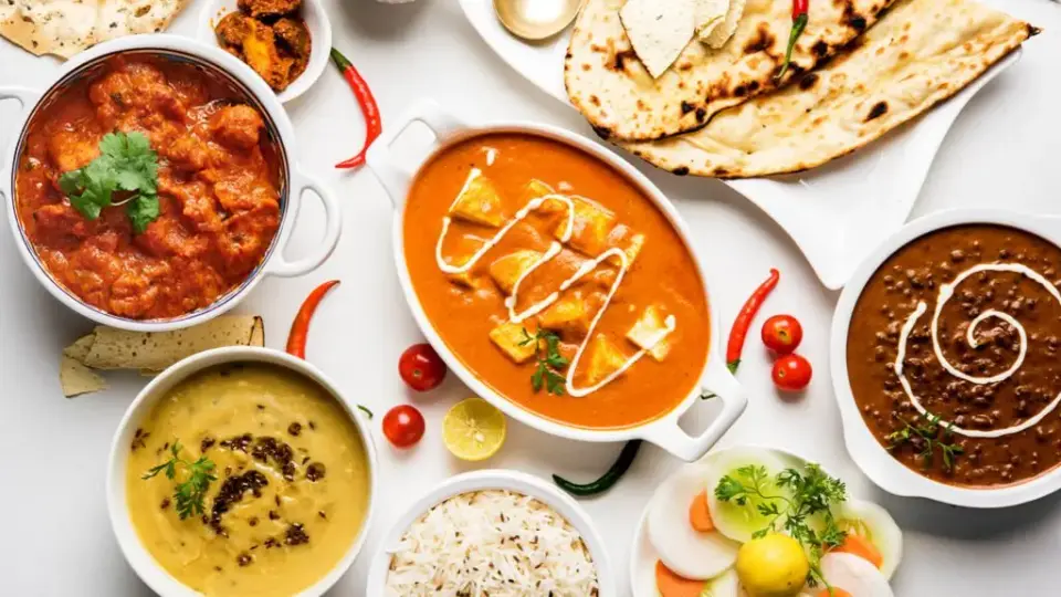 Overhead spread of curries, naan and rice on a table